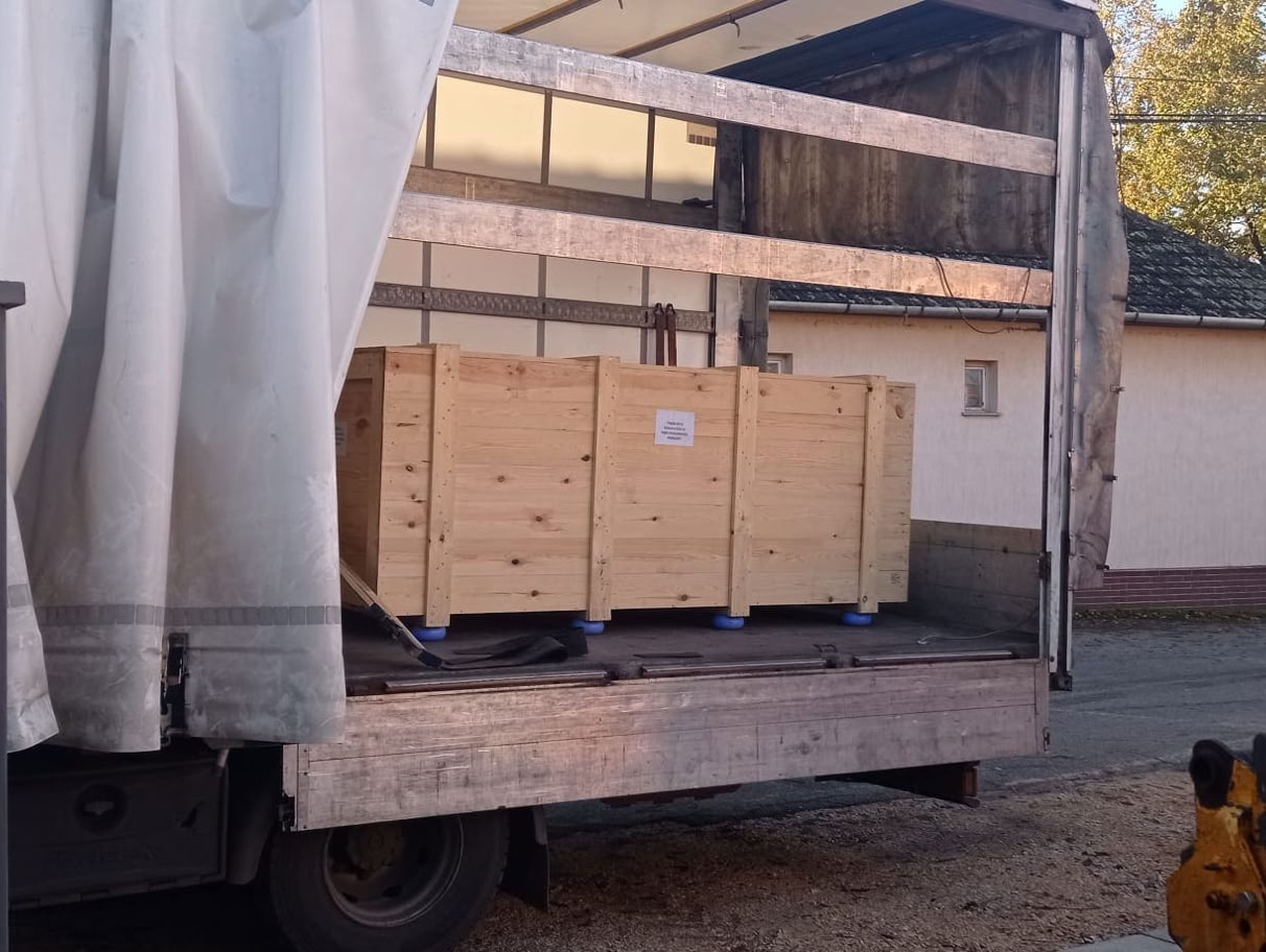An open truck with a telephone box standing in a large wooden box on the loading area.