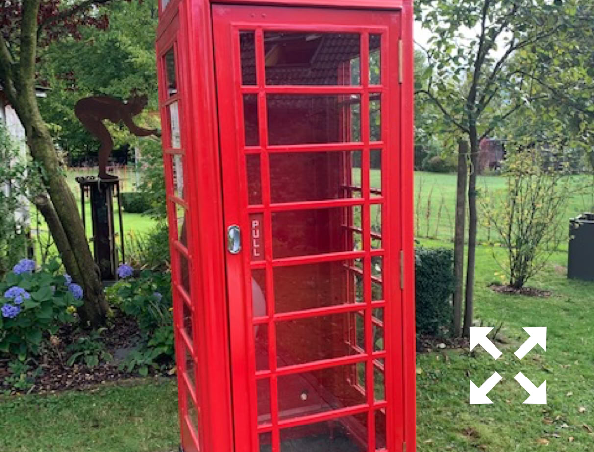 A red K6 telephone kiosk standing in a green garden