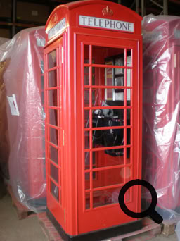 A red British telephone booth with glass panels, standing indoors.